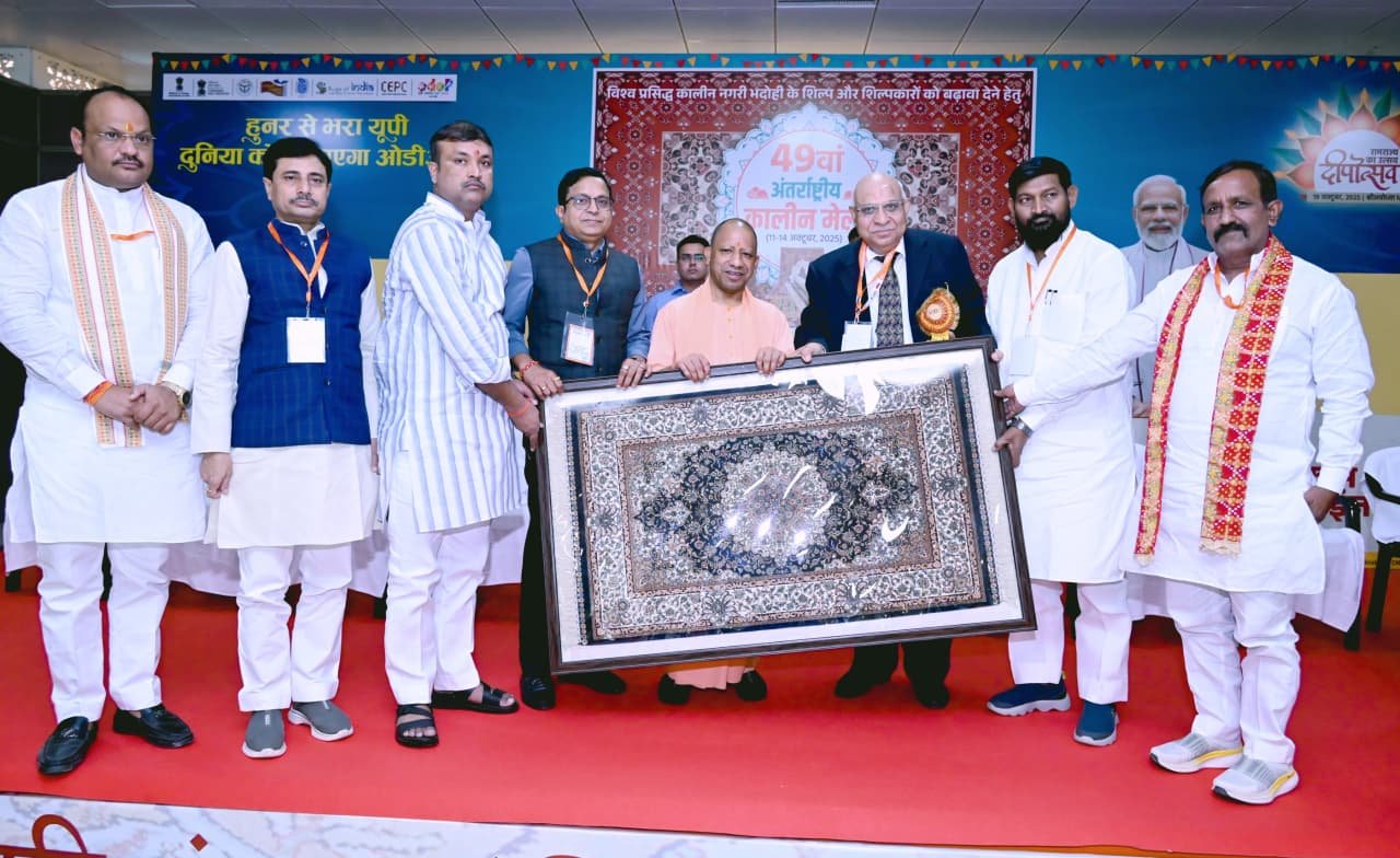 भदोही में मुख्यमंत्री योगी आदित्यनाथ ने 49वें अंतरराष्ट्रीय कालीन मेला और चौथे कार्पेट एक्सपो का शुभारंभ किया। उन्होंने अमेरिकी टैरिफ को अवसर बताते हुए कहा कि यूपी सरकार कार्पेट उद्योग को नए वैश्विक बाजारों से जोड़ने के लिए प्रतिबद्ध है। मुख्यमंत्री ने बताया कि यह उद्योग 30 लाख लोगों को रोजगार दे रहा है और महिला स्वावलंबन का बड़ा माध्यम बन चुका है। उन्होंने भदोही, मीरजापुर और वाराणसी को विकास कॉरिडोर के रूप में विकसित करने की घोषणा की तथा लाभार्थियों को करोड़ों के ऋण और सम्मान प्रदान किए।