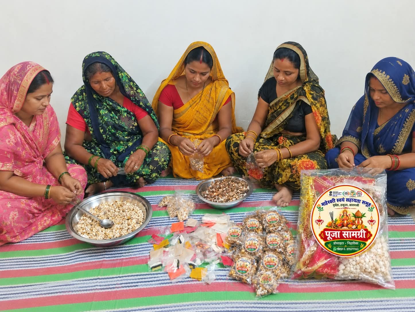 वाराणसी के हरहुआ ब्लॉक स्थित मुर्दहा गांव में माहेश्वरी स्वयं सहायता समूह की महिलाएं नवरात्र के लिए पूजा कॉम्बो पैक तैयार कर रही हैं। मां दुर्गा की चुनरी, रोली, चंदन, सिंदूर, अक्षत, धूप, कपूर, कलावा और हवन सामग्री से सजे इन पैकों को प्रेरणा मार्ट के माध्यम से बाजार मिल रहा है। वाराणसी में संचालित 65 प्रेरणा मार्ट ग्रामीण महिला उद्यमियों को बिक्री का अवसर दे रहे हैं। जानिए कैसे स्वयं सहायता समूह महिलाओं की आमदनी, आत्मविश्वास और आर्थिक आत्मनिर्भरता बढ़ाने में मददगार बन रहे हैं।