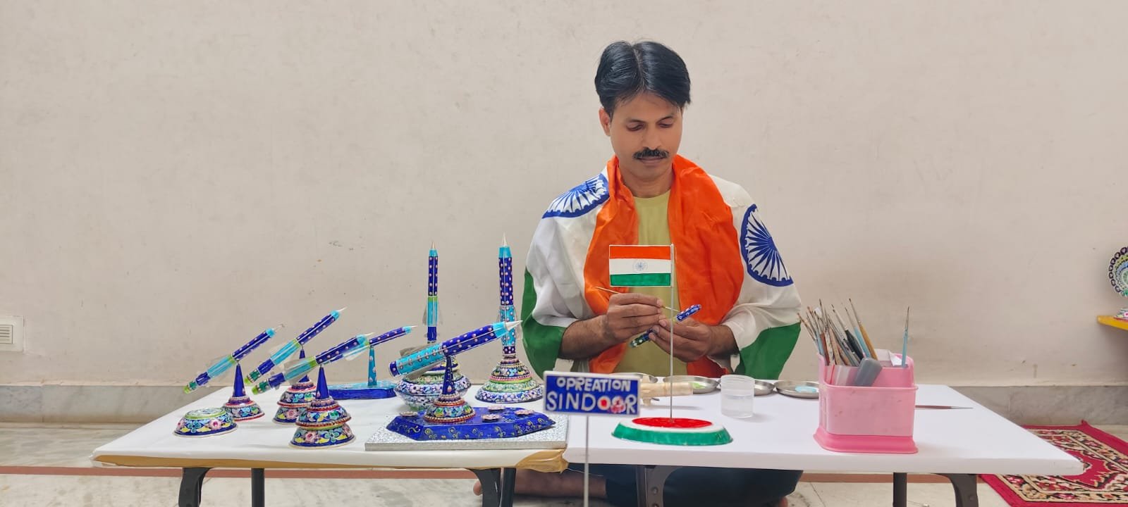 वाराणसी में ‘विंग्स ओवर गंगा’ एयर शो से प्रेरित राष्ट्रीय पुरस्कार विजेता शिल्पकार कुंज बिहारी सिंह ने गुलाबी मीनाकारी से लड़ाकू विमान की अनूठी कलाकृति तैयार की है। 400 ग्राम चांदी से बनी इस कलाकृति को तैयार करने में एक माह लगा। इसकी तस्वीर देखकर कैलिफोर्निया और ऑस्ट्रेलिया समेत विभिन्न स्थानों से करीब 100 पीस के ऑर्डर मिले हैं। जानिए कैसे काशी की पारंपरिक कला, भारतीय वायुसेना के शौर्य, ओडीओपी और जीआई उत्पादों से रोजगार एवं वैश्विक पहचान की नई संभावनाएं विकसित हो रही हैं।